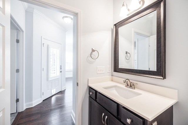 bathroom with vanity, crown molding, baseboards, and wood finished floors