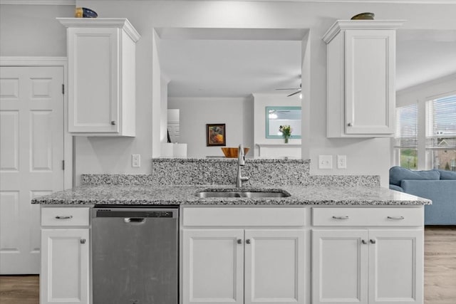 kitchen with white cabinetry, a sink, stainless steel dishwasher, and light stone counters