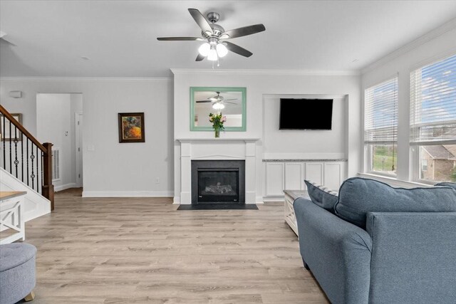 living area featuring light wood-style flooring, crown molding, and stairs