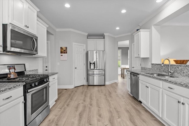 kitchen with a sink, white cabinetry, ornamental molding, and appliances with stainless steel finishes
