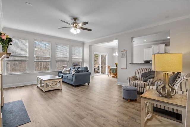 living area featuring ornamental molding, ceiling fan with notable chandelier, baseboards, and light wood-type flooring