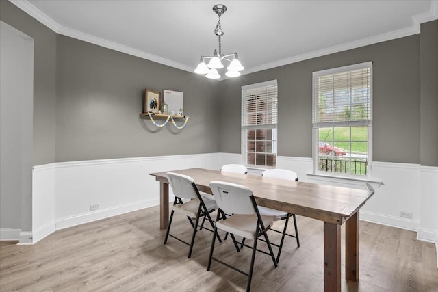 dining space with crown molding, baseboards, wood finished floors, an inviting chandelier, and wainscoting