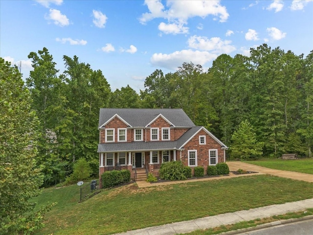 colonial-style house featuring brick siding, a front lawn, and covered porch