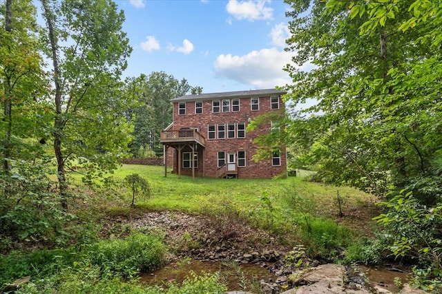 rear view of property with brick siding and a yard
