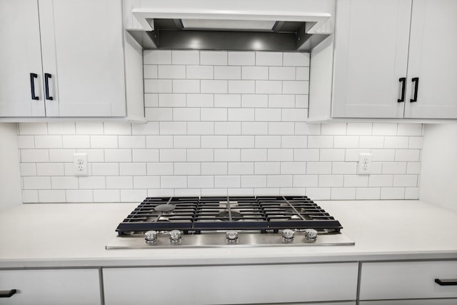 kitchen with stainless steel gas stovetop, decorative backsplash, light countertops, white cabinets, and premium range hood