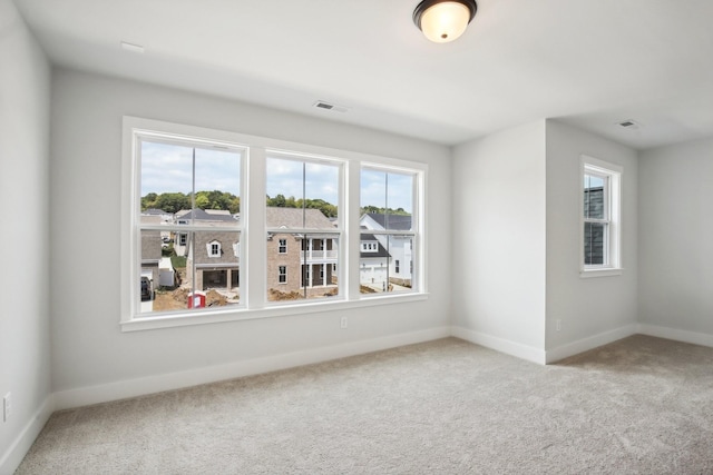 unfurnished room with baseboards, visible vents, and carpet