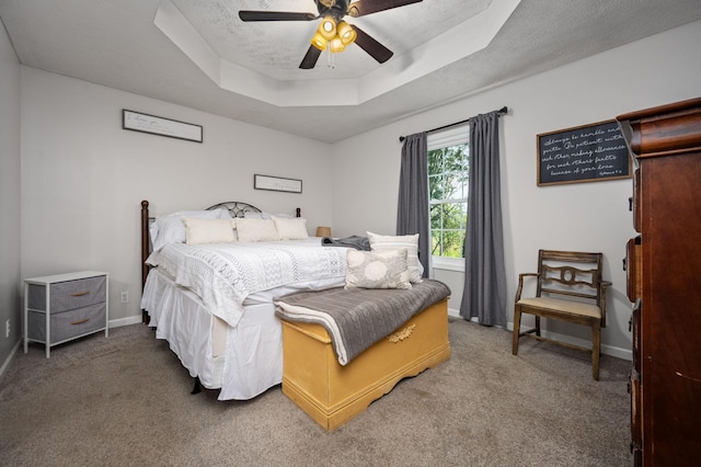 carpeted bedroom with a tray ceiling, baseboards, ceiling fan, and a textured ceiling