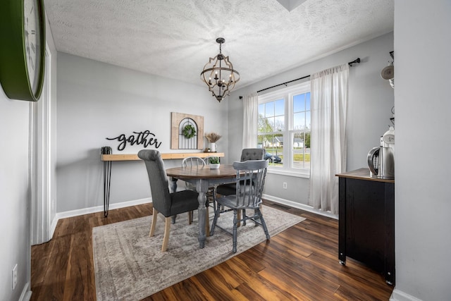 dining area with a textured ceiling, baseboards, wood finished floors, and an inviting chandelier