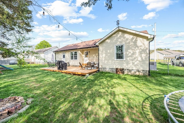 rear view of property with a lawn, fence, and a deck