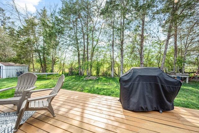 deck featuring a trampoline, a shed, an outbuilding, area for grilling, and a lawn