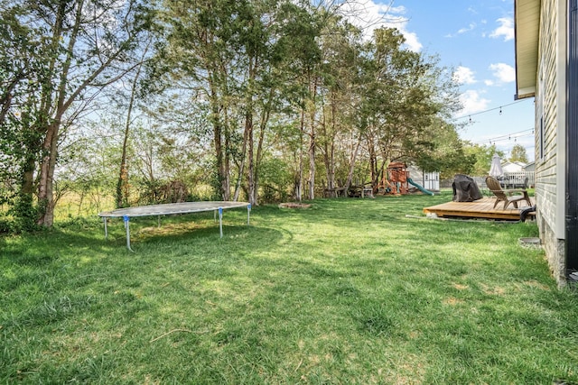 view of yard with a trampoline, a playground, and a wooden deck