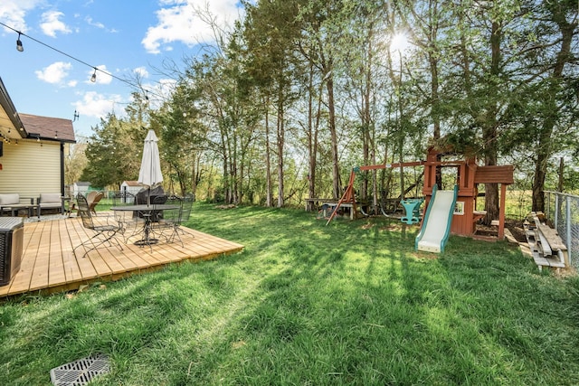 view of yard with fence, a deck, and a playground