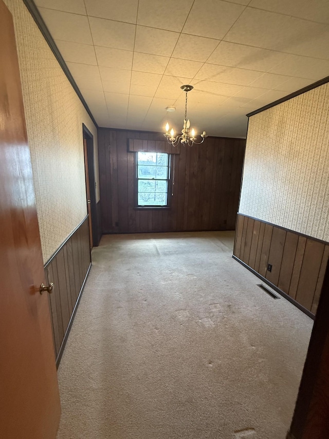 unfurnished room featuring ornamental molding, visible vents, a chandelier, and light colored carpet