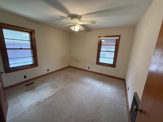 spare room featuring baseboards, visible vents, a ceiling fan, and light colored carpet