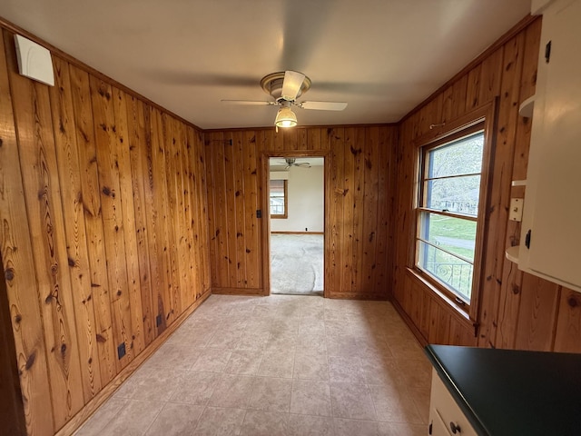 unfurnished room featuring wood walls, baseboards, and ceiling fan