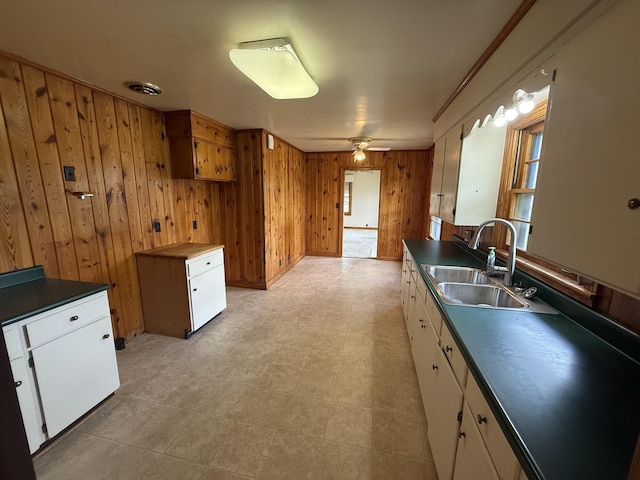 kitchen featuring visible vents, wood walls, dark countertops, white cabinetry, and a sink
