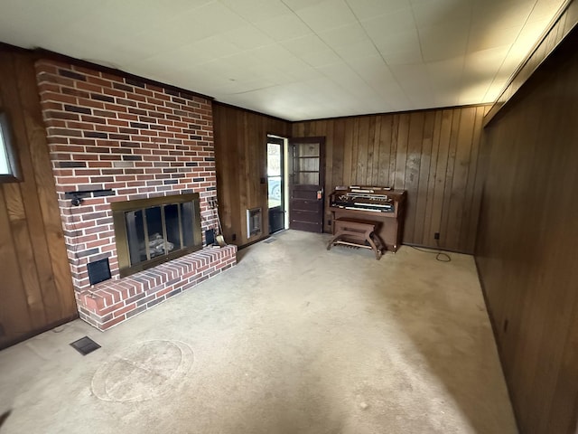 living room with light colored carpet, a fireplace, visible vents, and wood walls