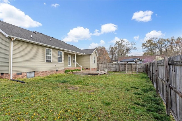 back of property with a fenced backyard, crawl space, a deck, and a lawn