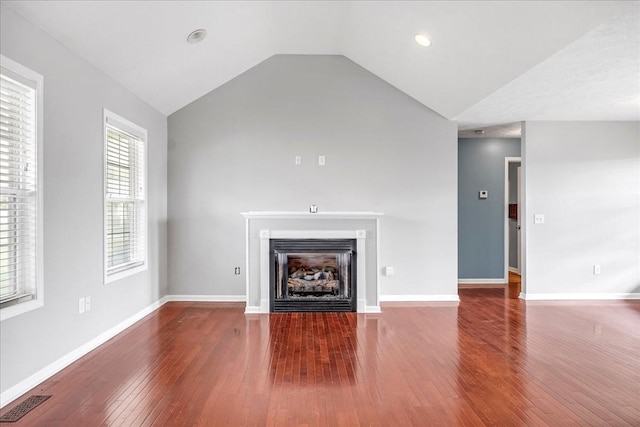 unfurnished living room with lofted ceiling, baseboards, hardwood / wood-style flooring, visible vents, and a fireplace