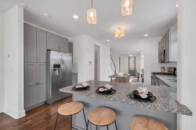 1603A 9th Ave N, Nashville, TN 37208 - kitchen featuring a breakfast bar area, gray cabinets, a peninsula, and appliances with stainless steel finishes