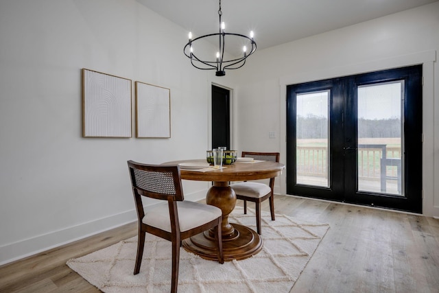 dining area featuring an inviting chandelier, baseboards, light wood-style floors, and french doors