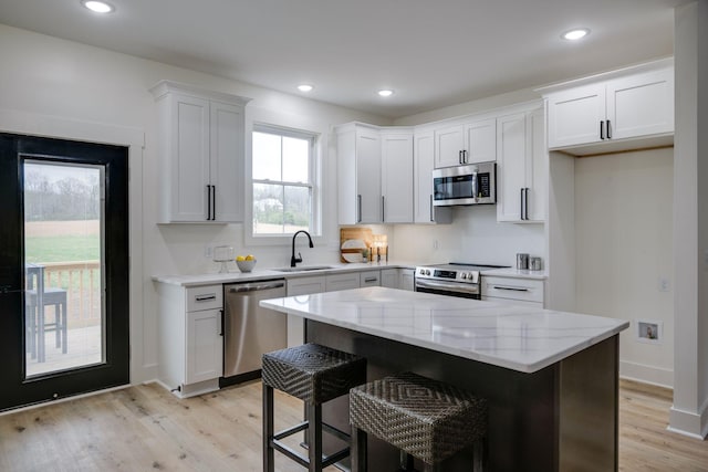 kitchen with light stone counters, light wood-style flooring, a sink, and stainless steel appliances