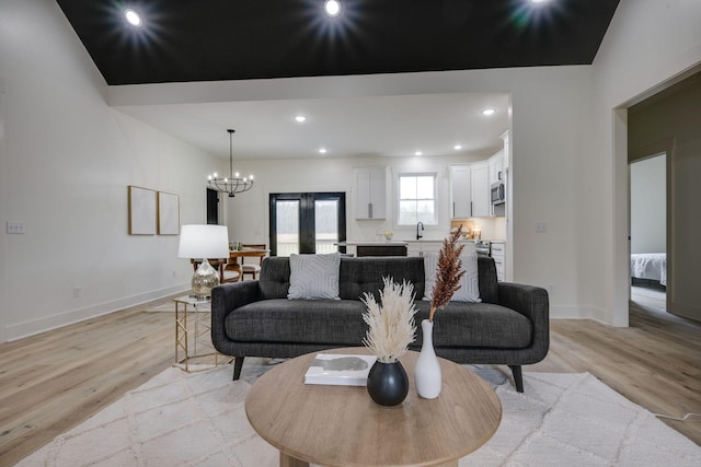 living room with baseboards, light wood-style flooring, recessed lighting, and a notable chandelier