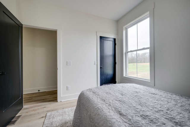 bedroom featuring baseboards, light wood-style flooring, visible vents, and a closet