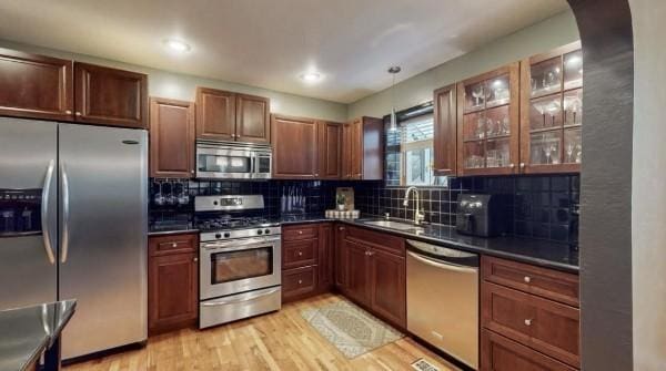 kitchen with stainless steel appliances, a sink, dark countertops, tasteful backsplash, and recessed lighting