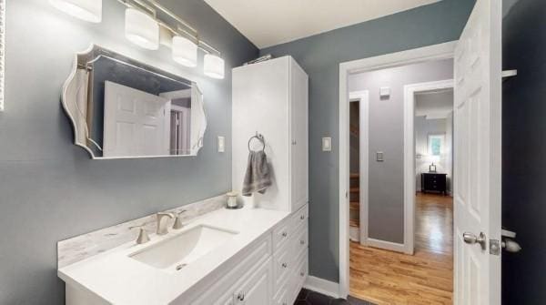 bathroom featuring vanity, wood finished floors, and baseboards