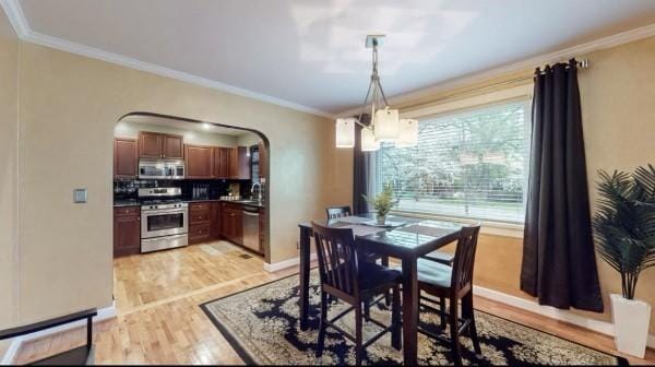 dining area with arched walkways, ornamental molding, light wood-style flooring, a chandelier, and baseboards