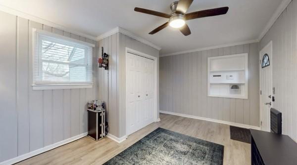 foyer with ornamental molding, ceiling fan, wood finished floors, and baseboards