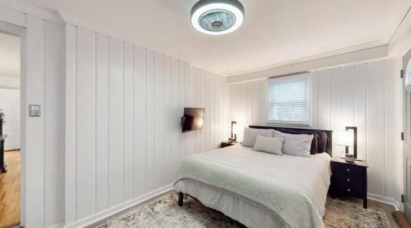 bedroom with wood finished floors, baseboards, and ornamental molding