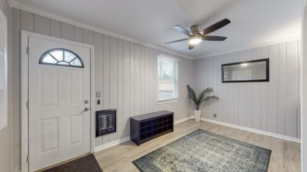 entryway with wood finished floors, plenty of natural light, crown molding, a ceiling fan, and baseboards