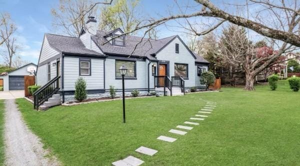 view of front of house with an outbuilding, a front yard, a chimney, driveway, and a detached garage