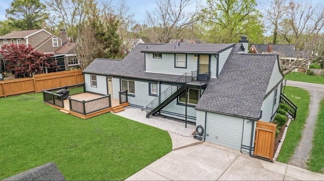 rear view of house with a shingled roof, a deck, a patio, and a chimney