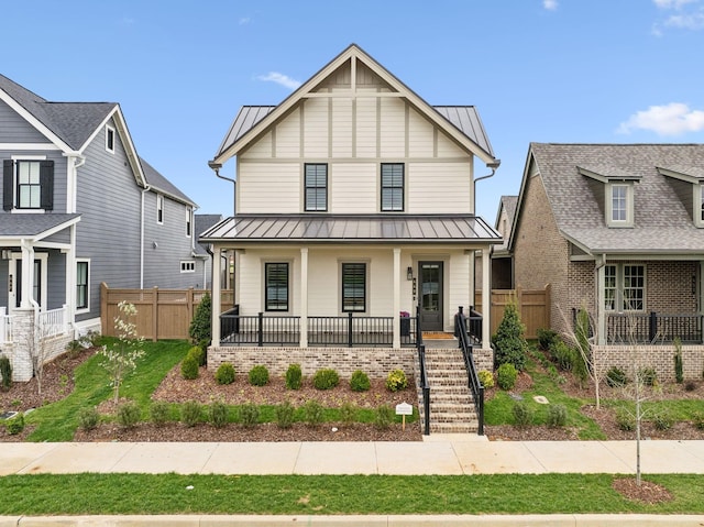 view of front of house featuring metal roof, a standing seam roof, fence, and a porch