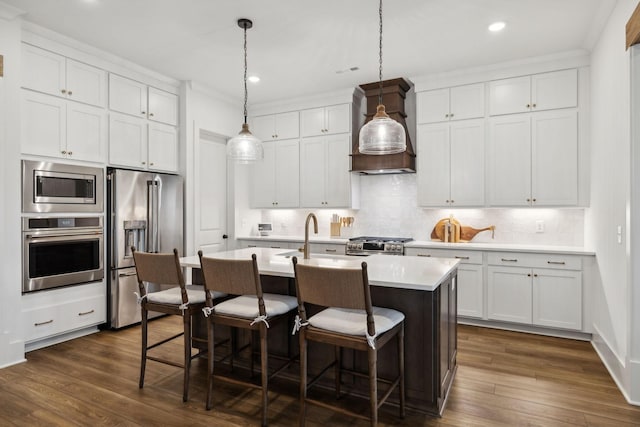 kitchen with dark wood finished floors, a breakfast bar, appliances with stainless steel finishes, and premium range hood
