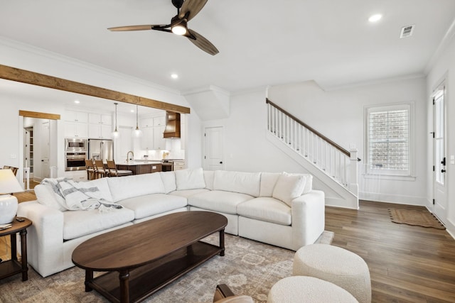 living area featuring stairs, crown molding, a ceiling fan, wood finished floors, and recessed lighting