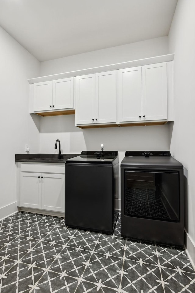 clothes washing area with washing machine and clothes dryer, dark floors, baseboards, a sink, and cabinet space