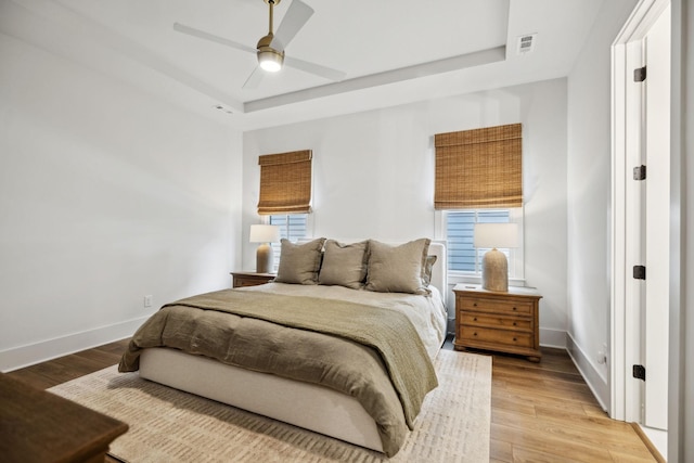 bedroom featuring visible vents, light wood-style floors, and a raised ceiling