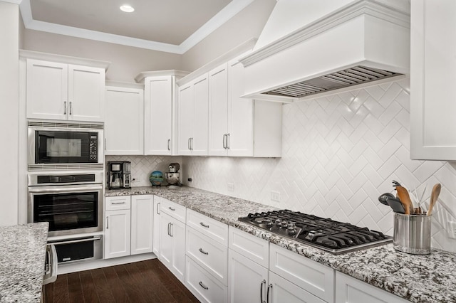 1701 Glen Echo Rd, Nashville, TN 37215 - kitchen featuring appliances with stainless steel finishes, dark wood finished floors, custom range hood, white cabinets, and ornamental molding