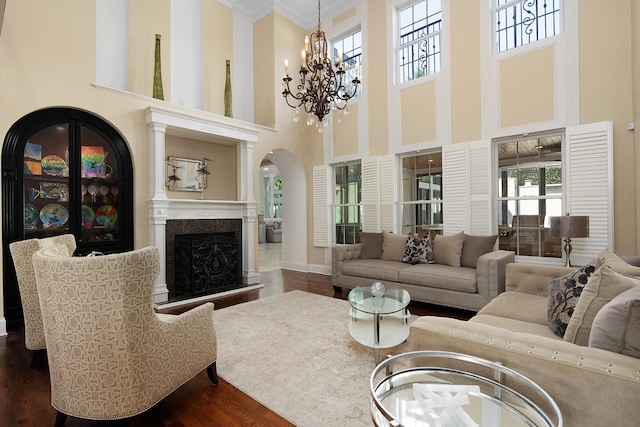 9812 Windrose Cir, Chattanooga, TN 37421 - living room featuring a high end fireplace, crown molding, arched walkways, dark wood-type flooring, and a notable chandelier