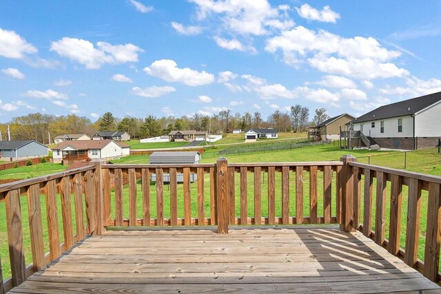 wooden terrace featuring a residential view, fence, and a lawn