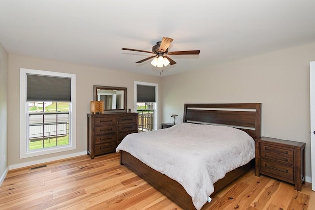 bedroom with light wood-type flooring, baseboards, multiple windows, and visible vents