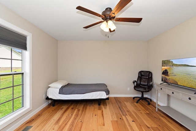 bedroom with multiple windows, baseboards, and light wood-style floors