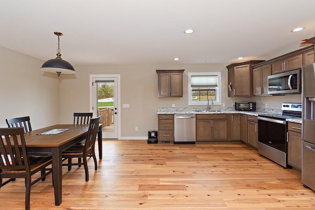 kitchen with a sink, light wood-style flooring, stainless steel appliances, recessed lighting, and dark brown cabinets