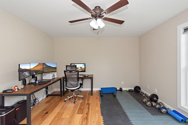office space featuring a ceiling fan, baseboards, and wood finished floors