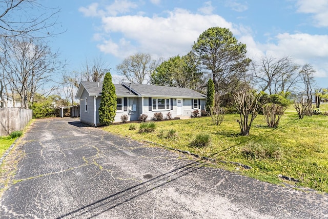 ranch-style home featuring a front lawn, fence, and driveway