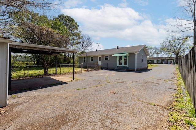 rear view of property with driveway, entry steps, fence, and french doors